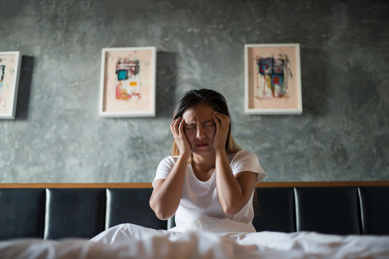 Depressed woman with a headache, hand holding her head on the bed.